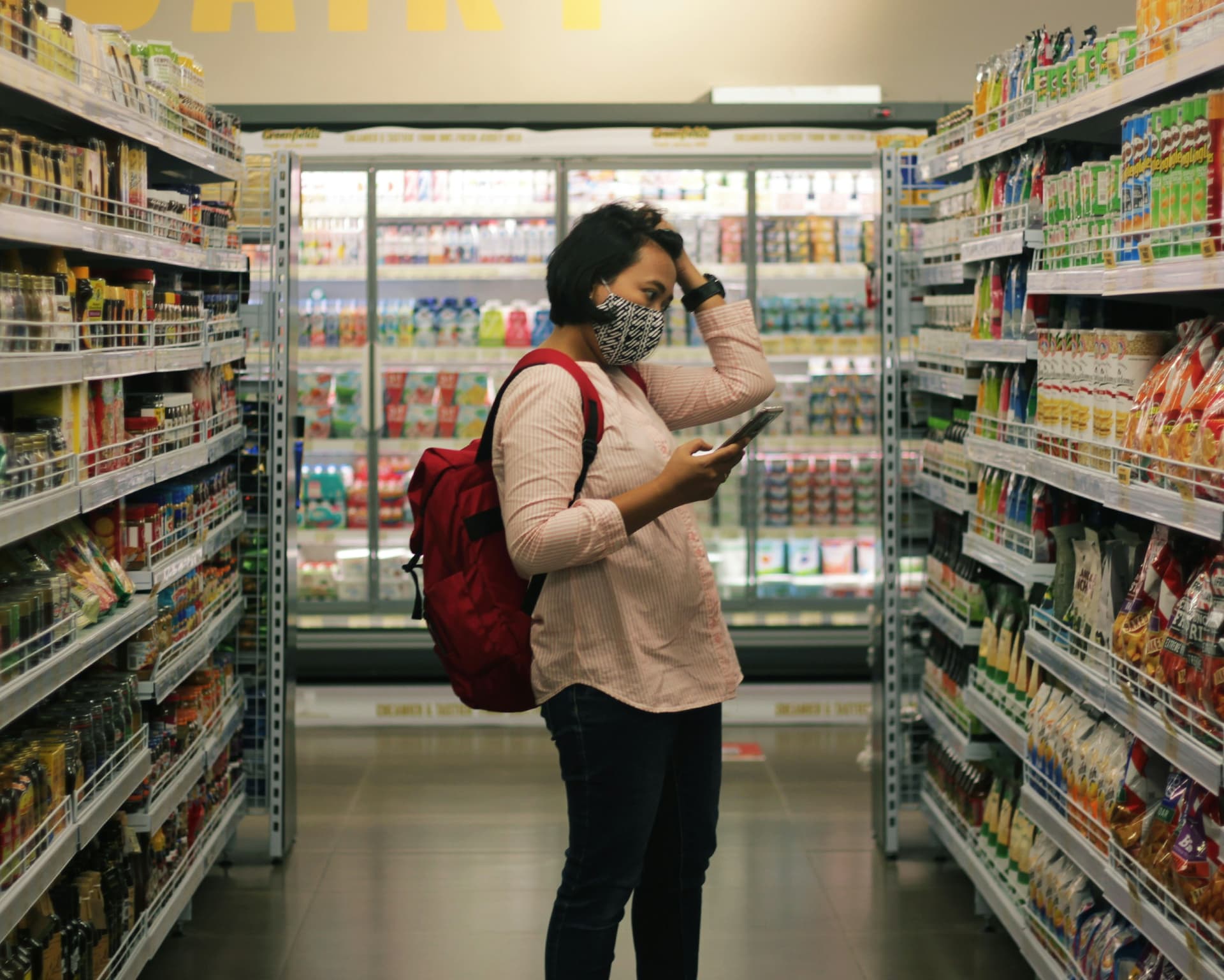 Imagem do hero, uma pessoa olhando o celular dentro do supermercado